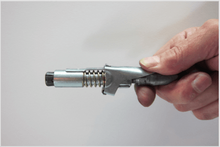 Close-up of a hand holding a LockNLube® grease coupler for maintenance and repair, showcasing its design features.