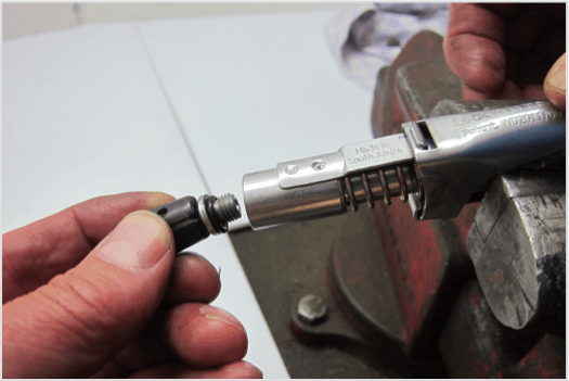 Person replacing the seal on a LockNLube® grease coupler using a rebuild kit in a workshop.