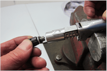 Person replacing the seal on a LockNLube® grease coupler using a rebuild kit in a workshop.
