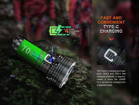 Fenix LR40Rv2 flashlight charging with Type-C port, showing 70% battery level on a rocky surface.