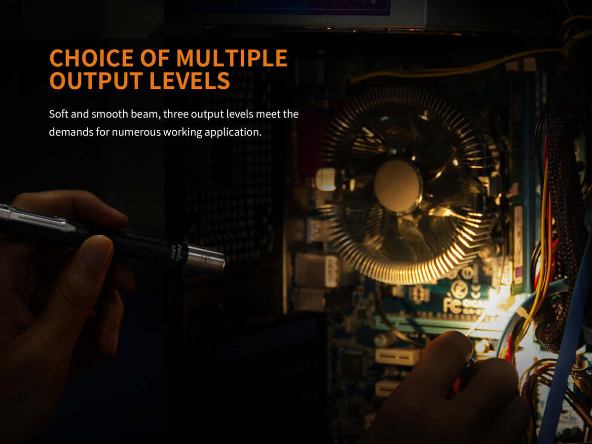 Hand using a flashlight with multiple output levels to illuminate a computer's interior components.