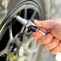 Hand using LOCKNFLATE® locking air chuck on tire valve for secure, hands-free inflation connection.