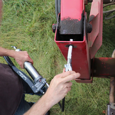 User applying the LockNLube® grease gun coupler to machinery for efficient greasing without leaks or pressure issues.