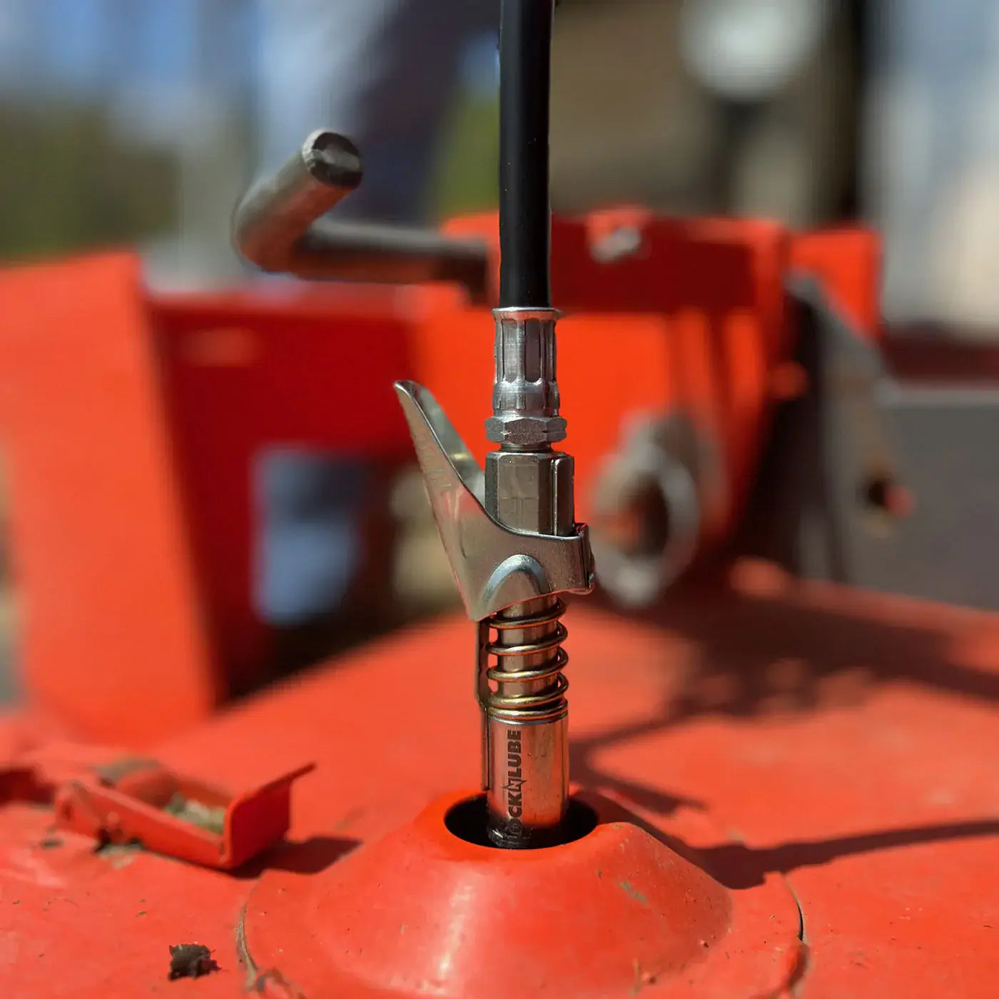 Close-up of LockNLube® grease gun coupler securely attached to a grease fitting for efficient lubrication without leaks.